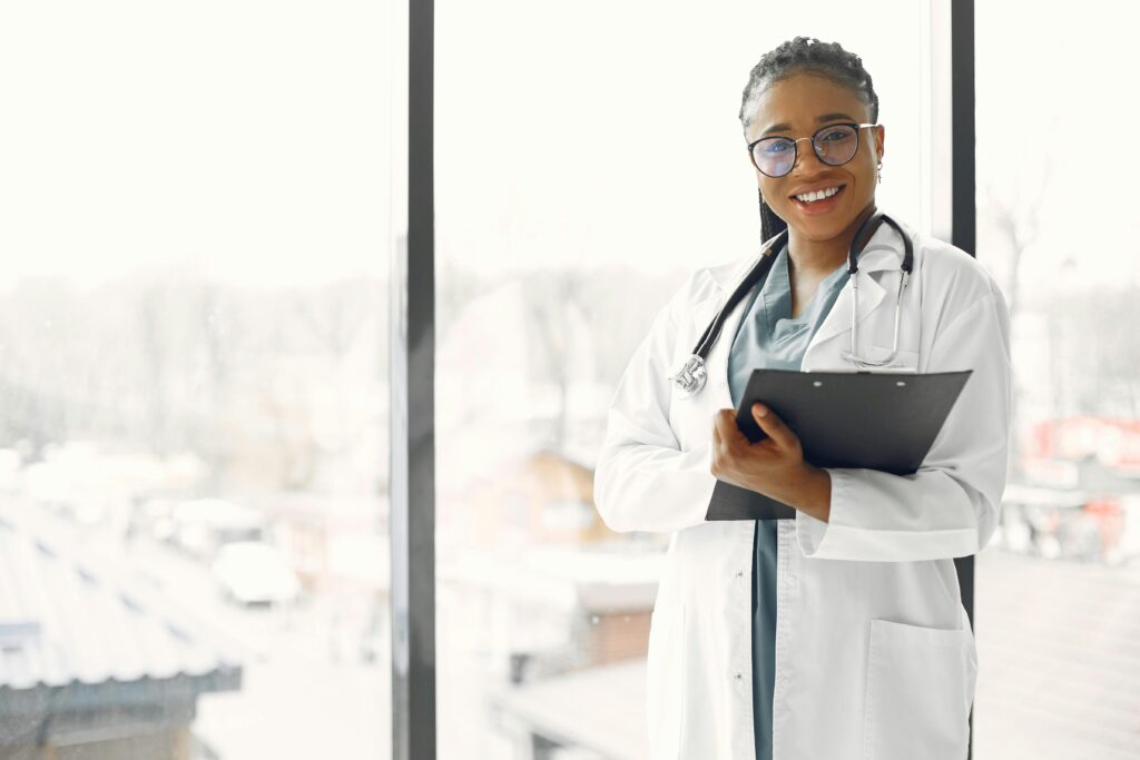 Professional female doctor smiling confidently holding a clipboard indoors.